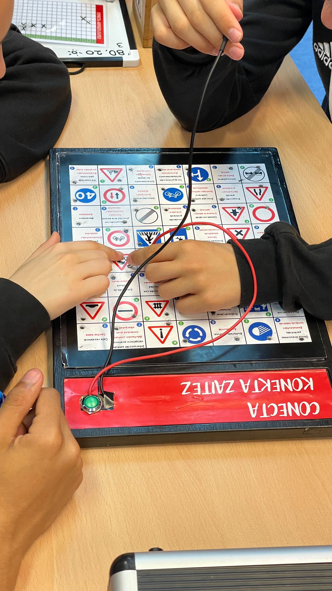 Manos de niños interactuando con un tablero de señales de tráfico en un Escape Room.