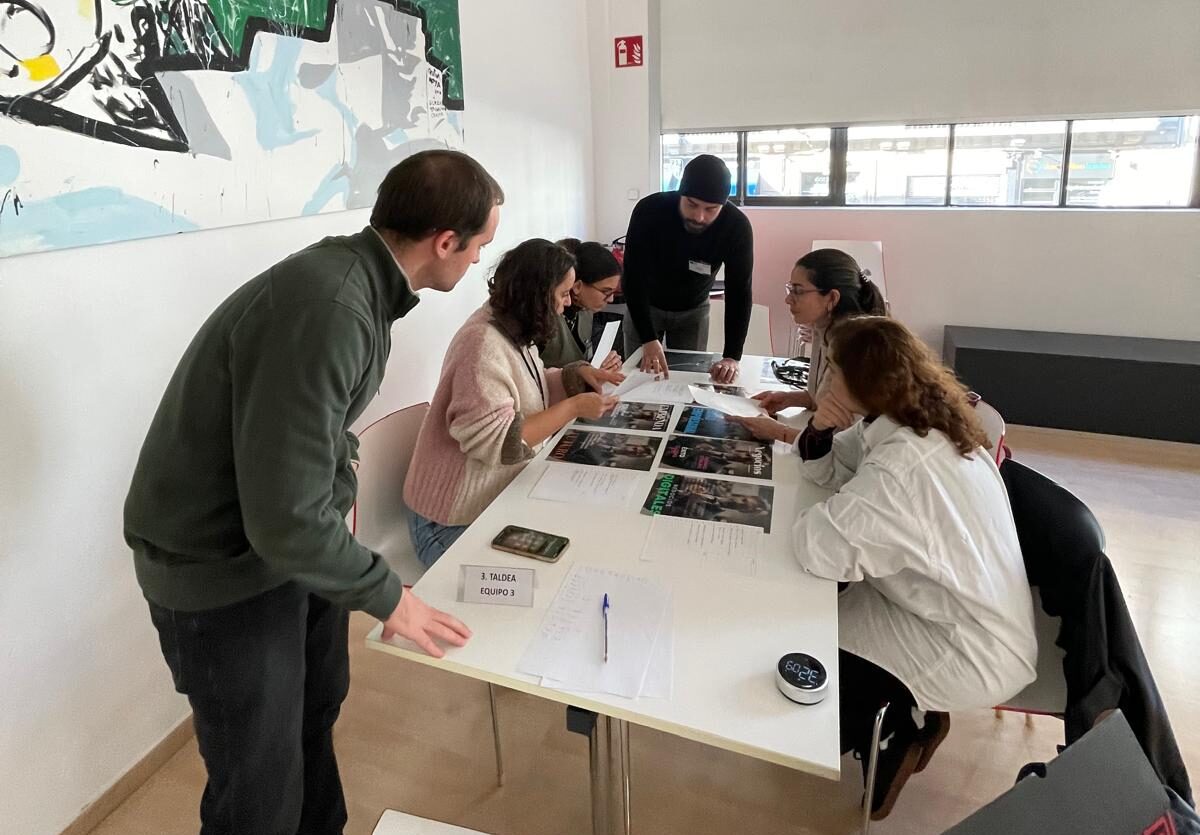 Grupo de personas colaborando en una mesa, revisando documentos y fotografías.