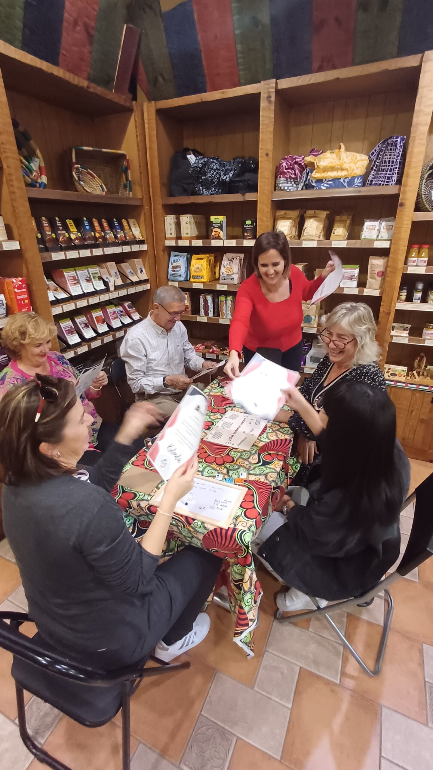 Grupo de personas sentadas alrededor de una mesa, participando en una actividad en un espacio decorado.