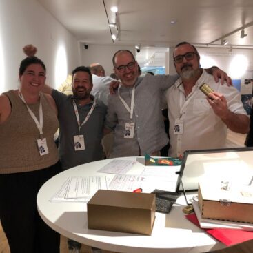 Cuatro personas sonrientes sosteniendo objetos en una mesa en un evento de Orkli.