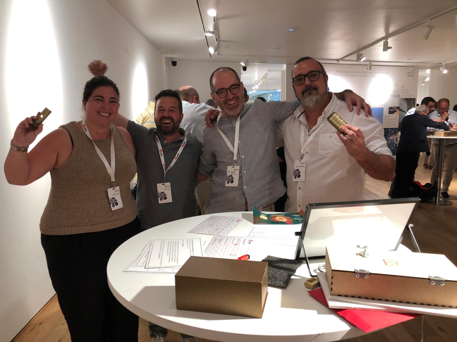 Cuatro personas sonrientes sosteniendo objetos en una mesa en un evento de Orkli.