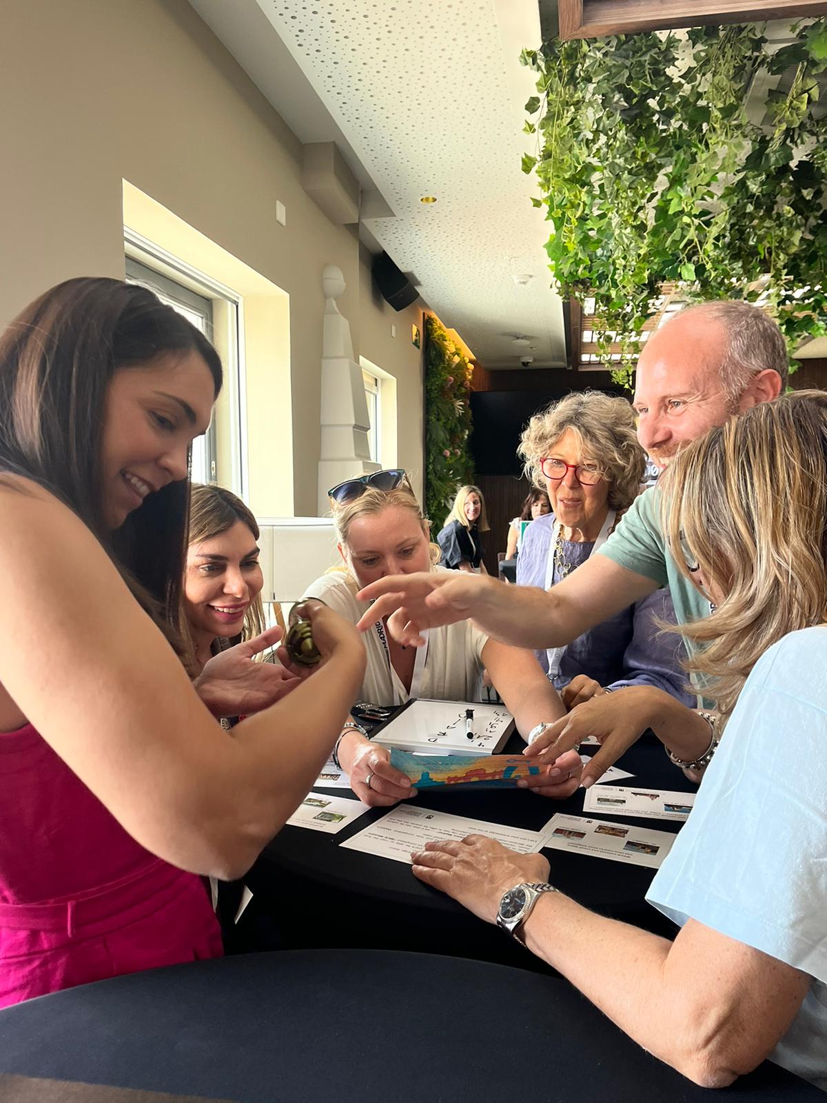 Grupo de personas interactuando y observando un objeto en una mesa durante un evento.