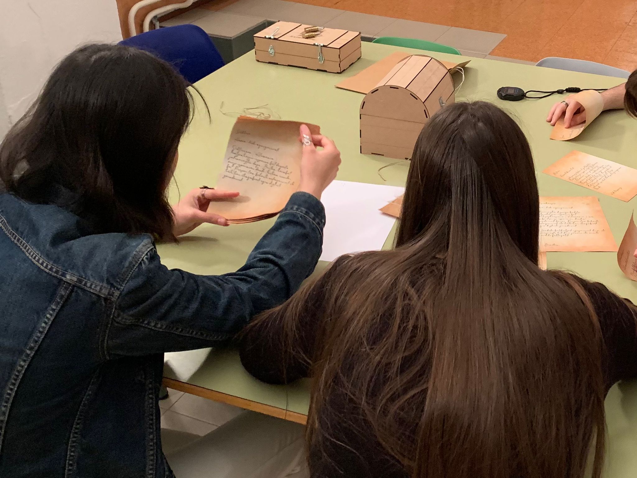 Dos personas sentadas en una mesa, revisando notas y cajas de madera.